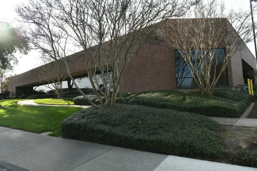 Trimmed shrub beds and lawn at a brick office building