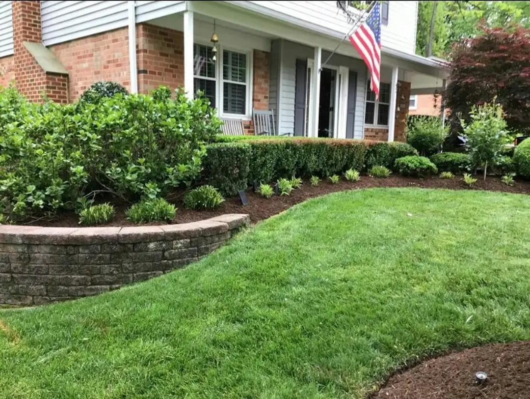 Fresh mulch beds, shrubs and a block retaining wall in front of a house