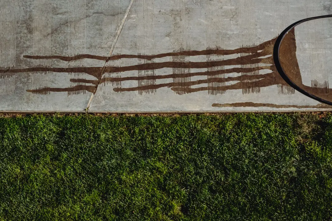 Pressure washing a dirty sidewalk next to a lawn
